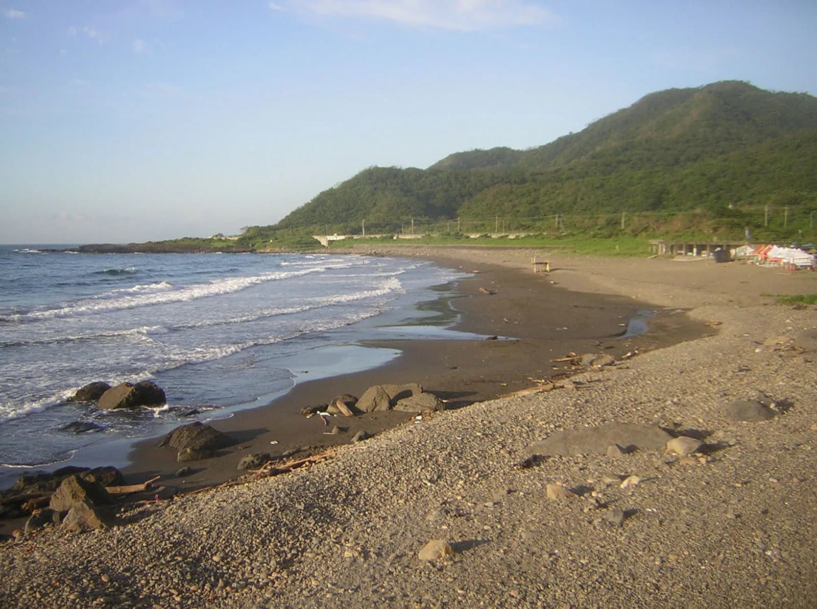 Pesisir pasir gelap melengkung, bebatuan, dan laut di Daxi Honeymoon Bay