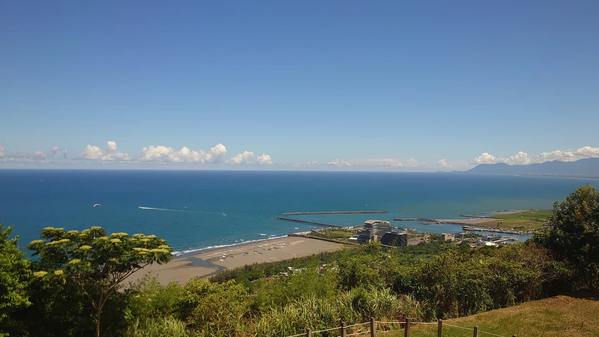 Pemandangan dari atas ke pantai pasir gelap Wai'ao, laut, dan pesisir luar Pelabuhan Wushi